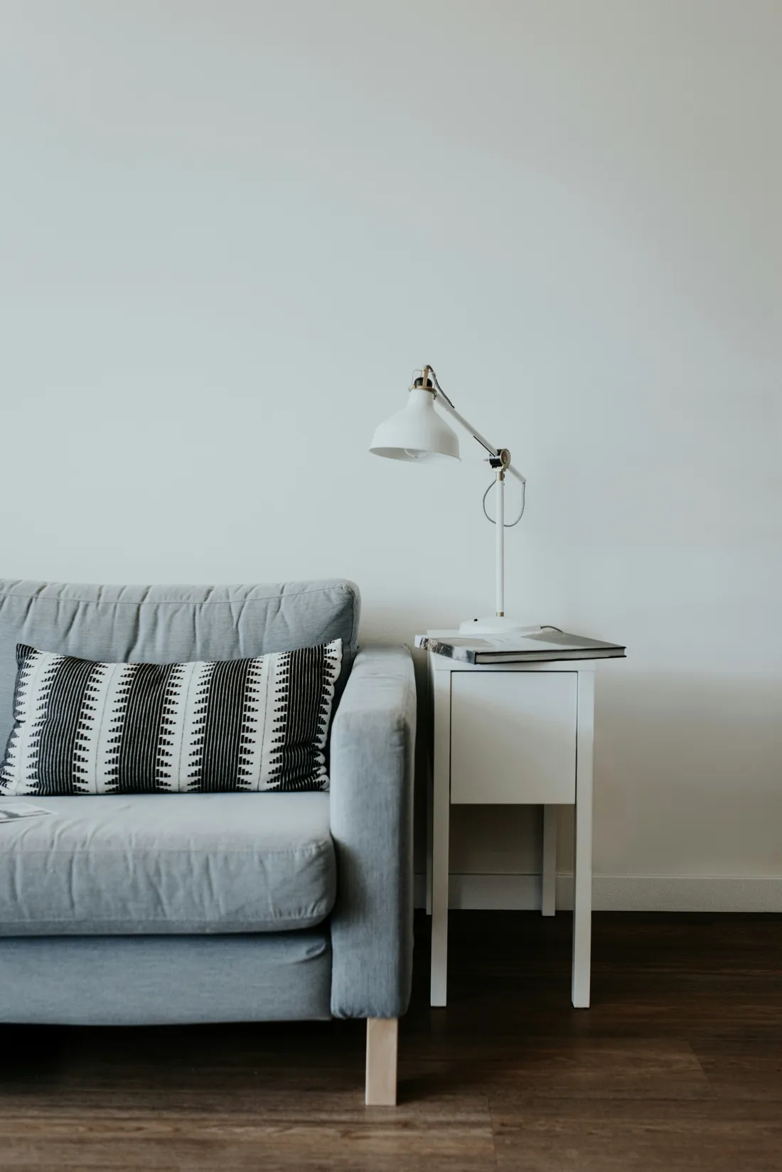 A calm living room corner with a gray armchair and a small lamp