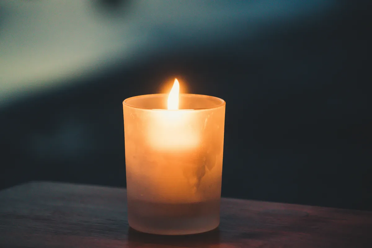 A lit votive candle in a dark room