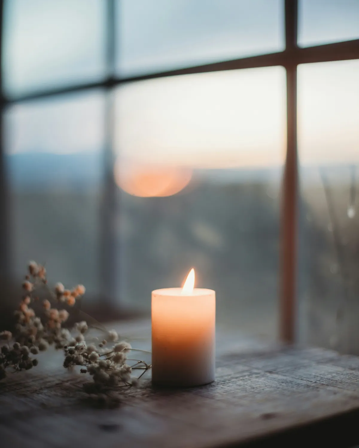 A candle in a window at sunset